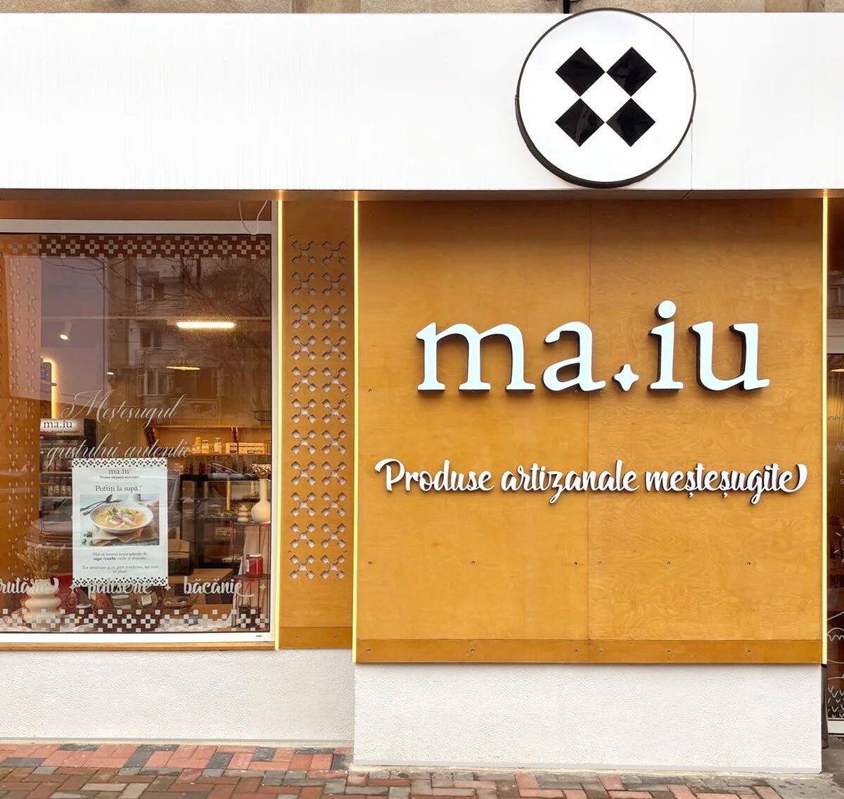 Fațada MA.IU: panou din lemn cu literele ma.iu, sloganul „Produse artizanale meșteșugite” și logo rotund